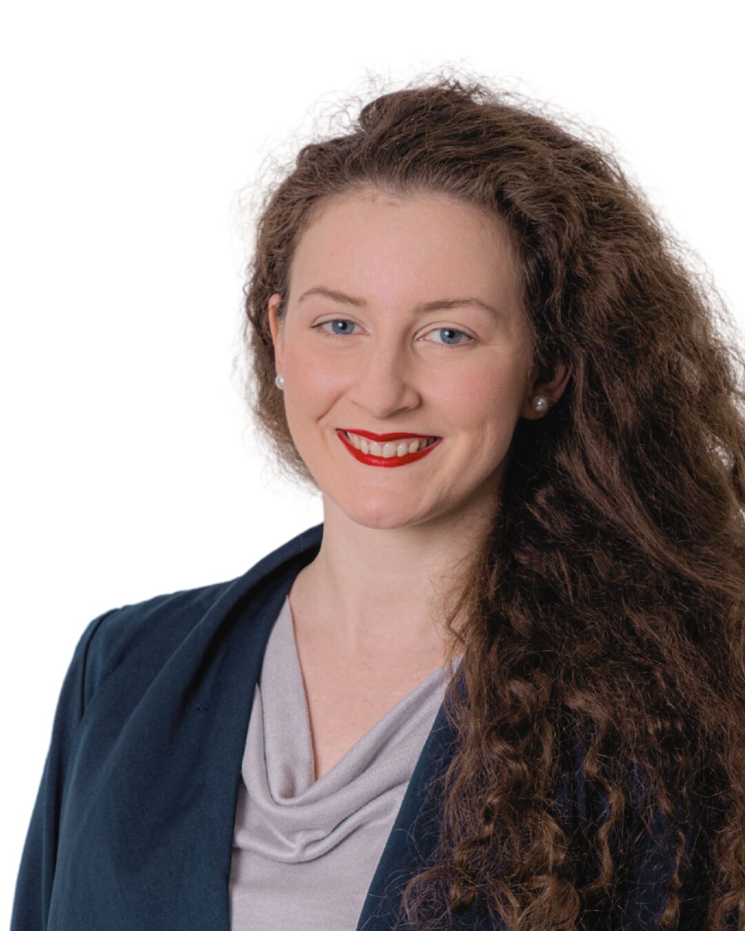 Portrait von Marketingleiterin der Firma Sanit Franziska Mölle im dunkelblauen Jackett mit hellgrauer Bluse darunter. Sie blickt mit offenen Haaren und rotem Lippenstift den Betrachter freundlich lächelnd an.